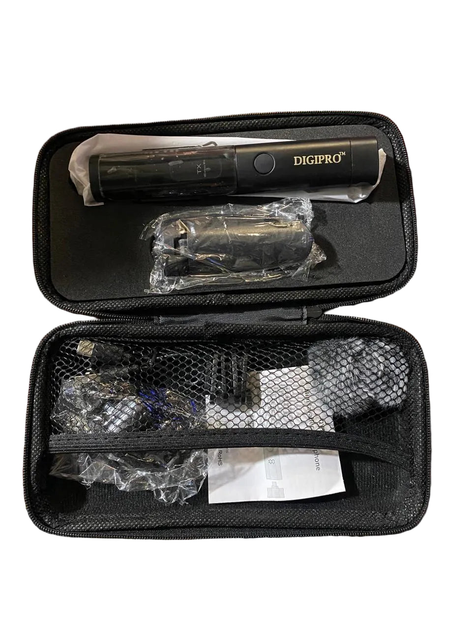A Digipro handheld mic in a black zippered carrying case, shown open on a wooden table with accessories and paperwork inside the mesh pocket.